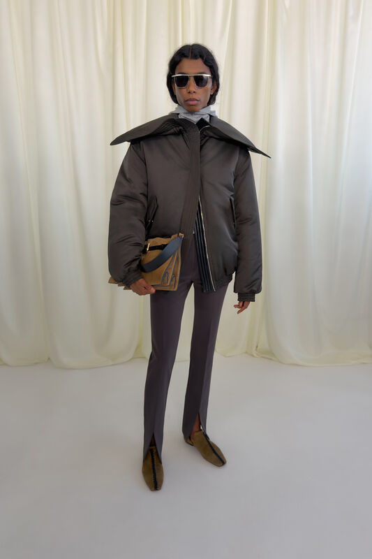 Модный лук с объемной курткой и строгими брюками с разрезами, дополненный стильной сумкой и солнечными очками