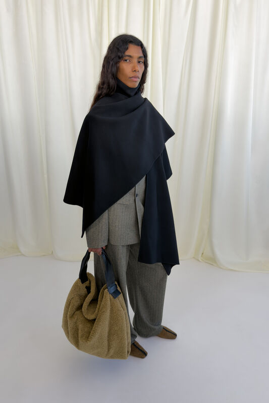 Стильный черный пончо в сочетании с серым костюмом и уютной сумкой из меха придают образу современный шик в сезоне осень-зима 2026 от Nanushka