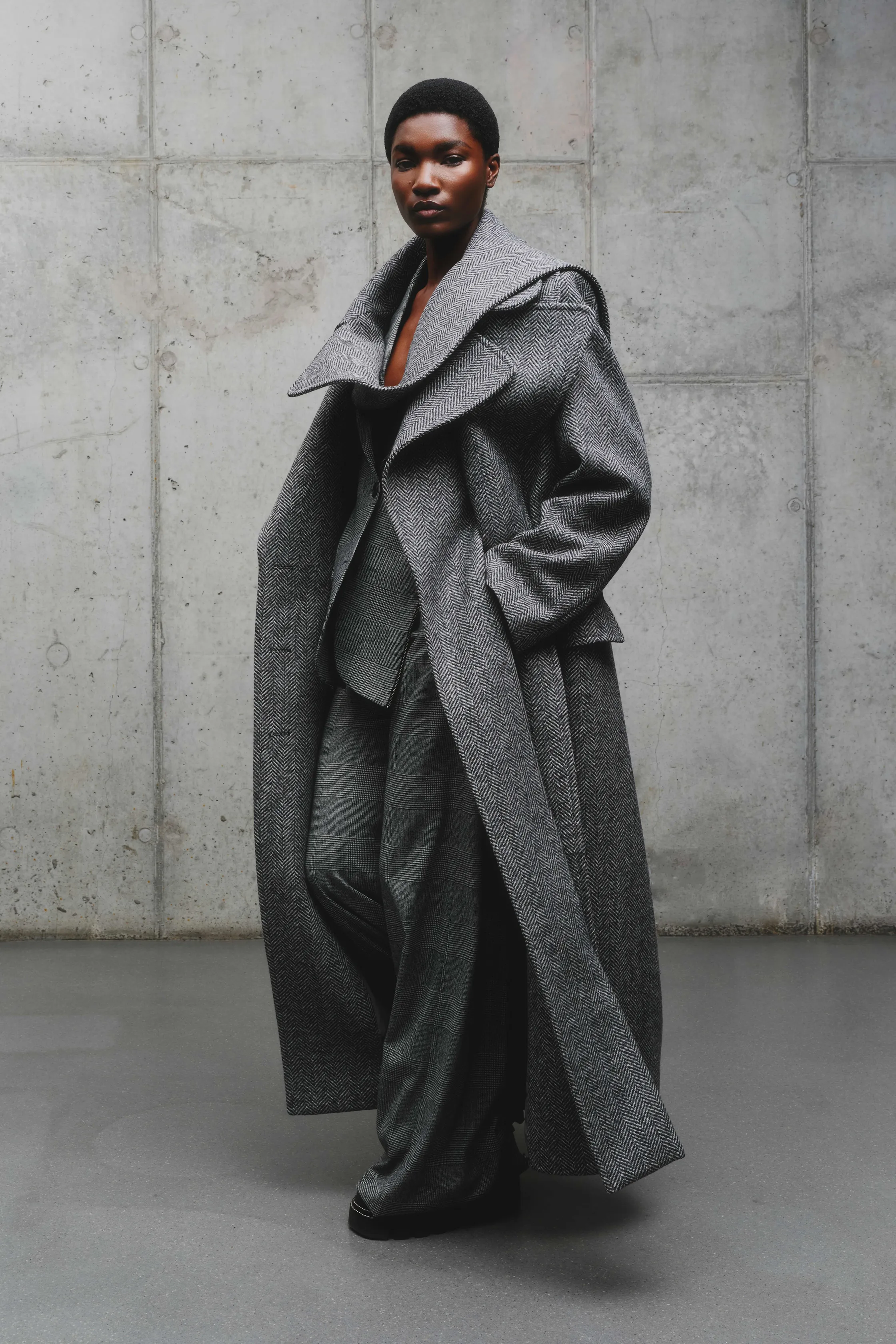 Объемный серый пальто с широкими лацканами, подчеркивающее силуэт, в сочетании с элегантным костюмом из той же ткани