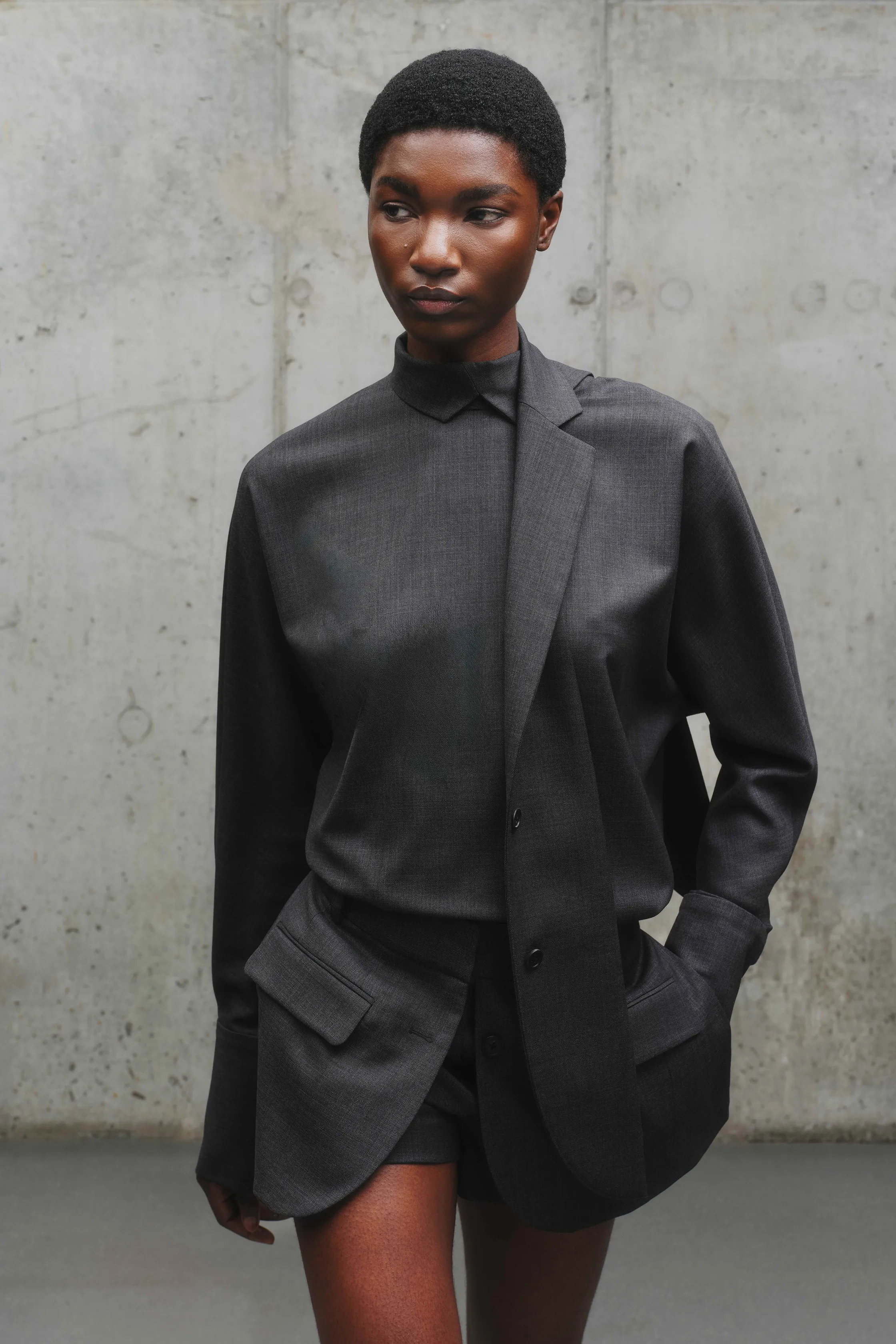 Минималистичный наряд в темных тонах: асимметричная рубашка с карманами и шорты, создающие стильный контраст