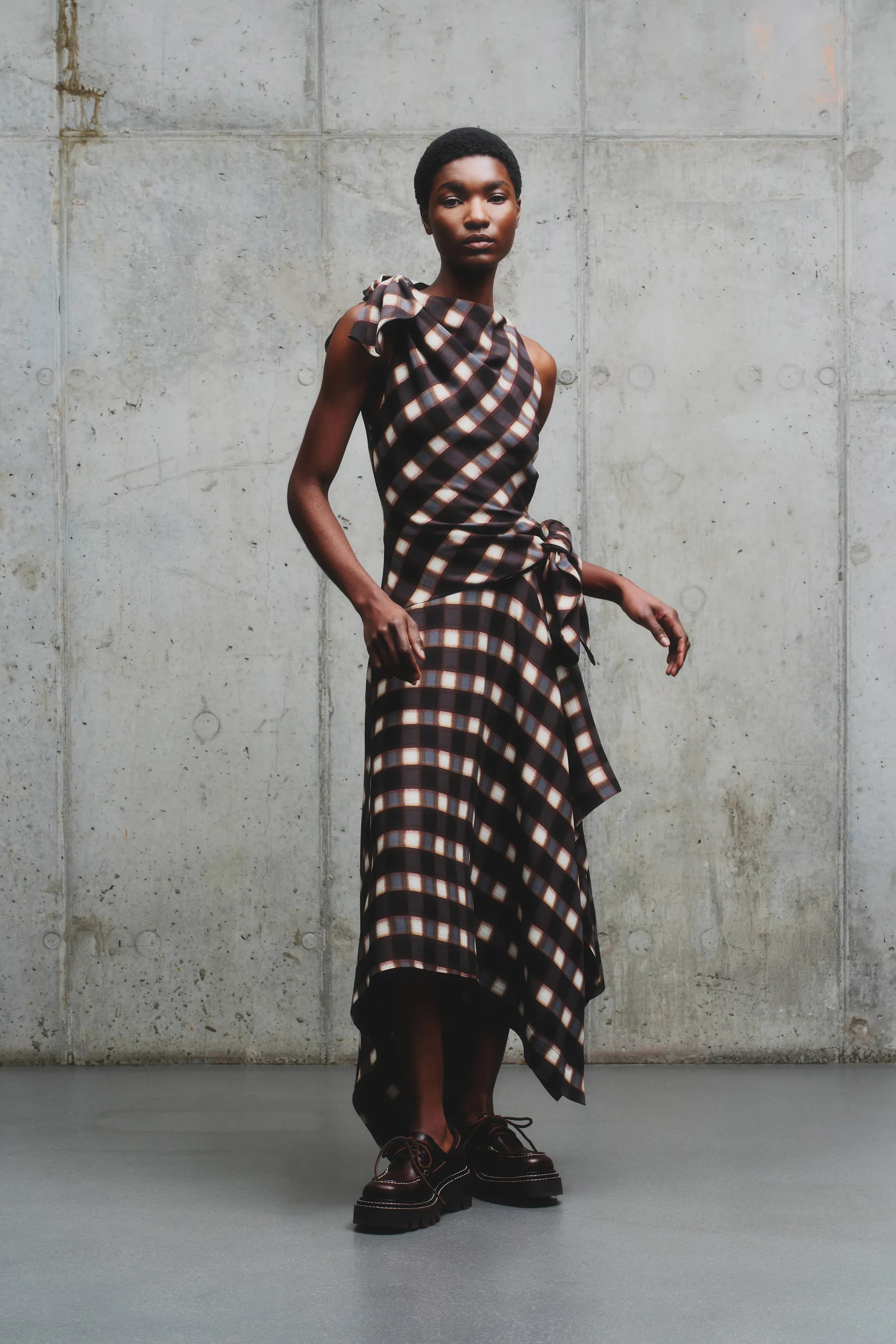 Платье с асимметричным кроем в клетку, сочетание коричневых и бежевых оттенков, акцент на текстуре ткани и обуви с платформой