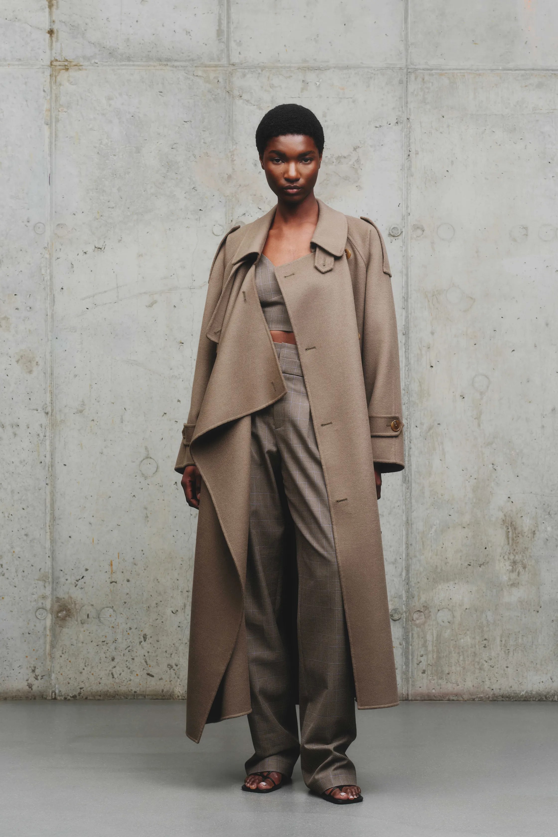 Элегантный образ в бежевом пальто и клетчатом костюме, акцент на текстуре тканей, минималистичный стиль с открытым животом
