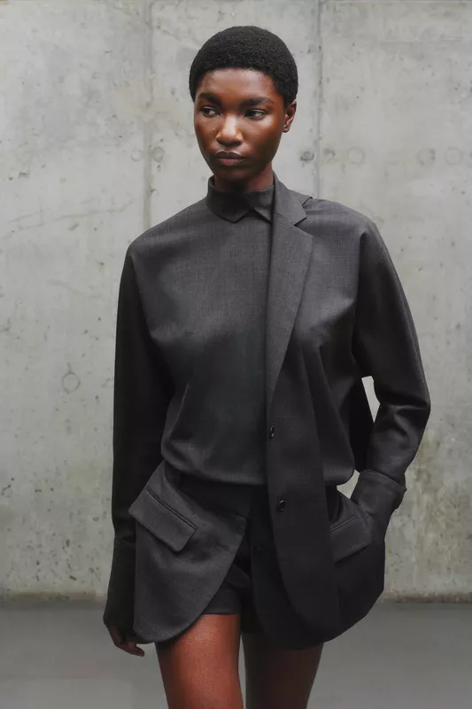 Минималистичный наряд в темных тонах: асимметричная рубашка с карманами и шорты, создающие стильный контраст