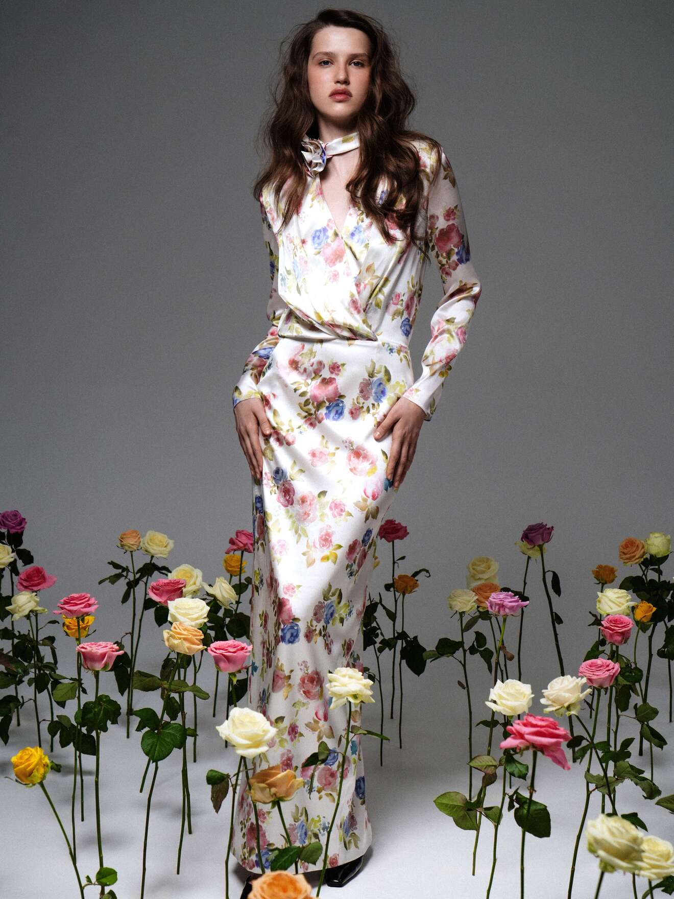 Элегантное платье с цветами и бантом на шее, подчеркивающее силуэт, на фоне цветущих роз