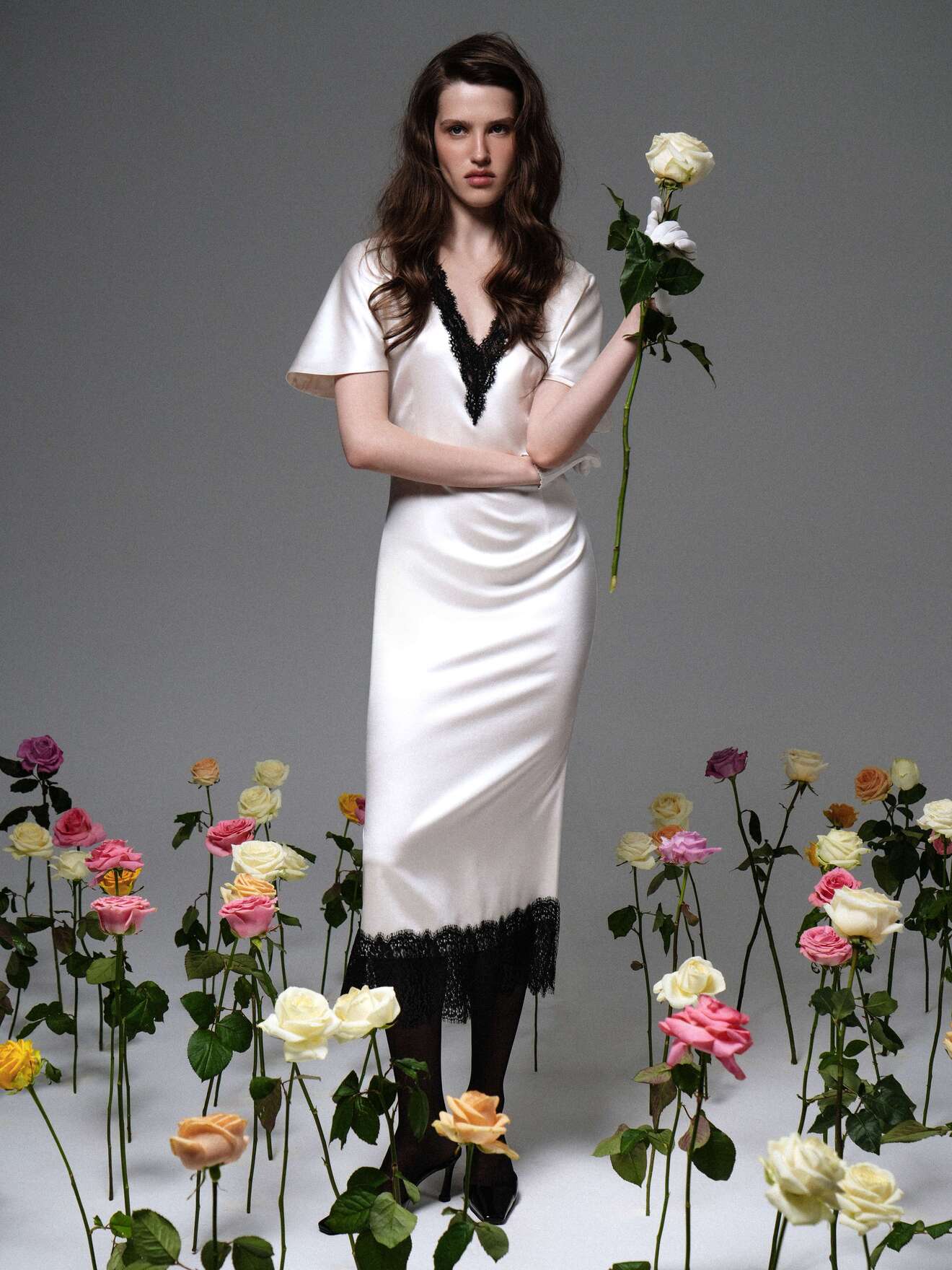 Шелковое платье с глубоким вырезом и кружевом, в окружении роз, передает атмосферу загадочной элегантности