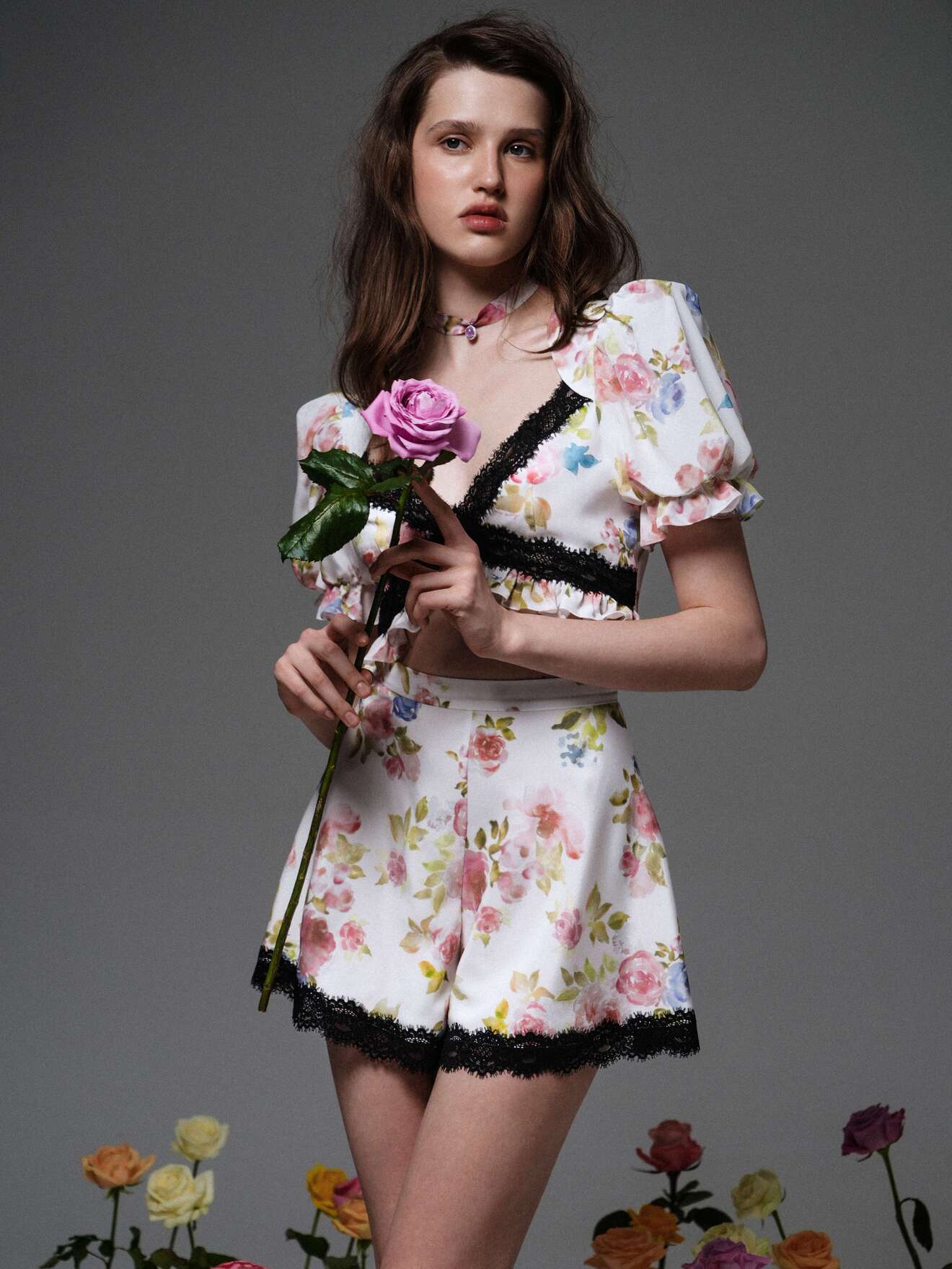 Короткий комплект с цветочным узором и черной кружевной отделкой, в руках — роза, создающая романтичный образ