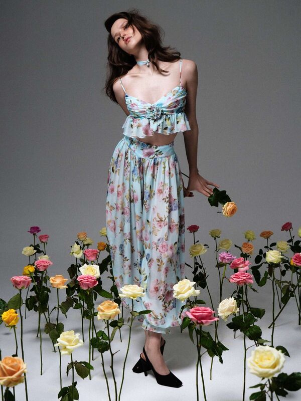 Нежный комплект из топа и юбки с цветочным узором, создающий игривый образ на фоне цветущих роз
