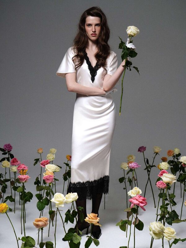 Шелковое платье с глубоким вырезом и кружевом, в окружении роз, передает атмосферу загадочной элегантности