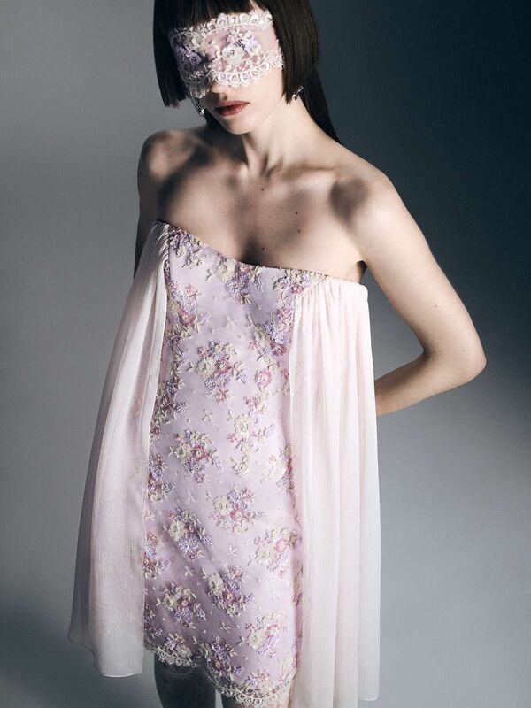 Нежное платье с цветочной вышивкой и прозрачными рукавами, дополненное кружевной маской, придающей образу таинственность
