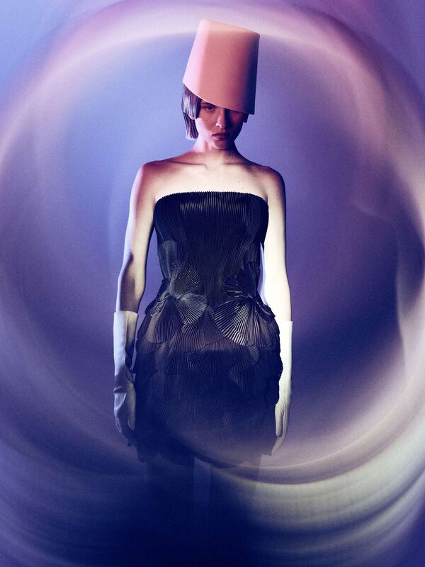 Экспериментальное платье с волнистыми складками и необычной шляпой, создающее футуристический образ