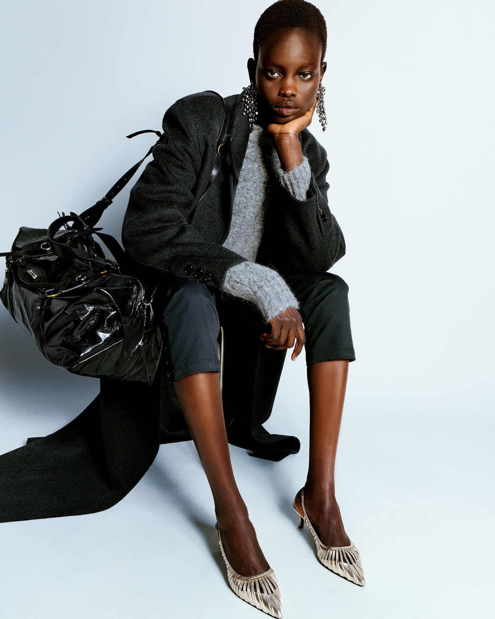 Стильный образ с серым свитером и длинным черным пальто, дополненный блестящими туфлями и объемной сумкой