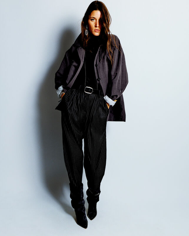 Строгий образ с серой курткой и полосатыми брюками, подчеркивающими силуэт, завершает эффектная обувь на высоком каблуке