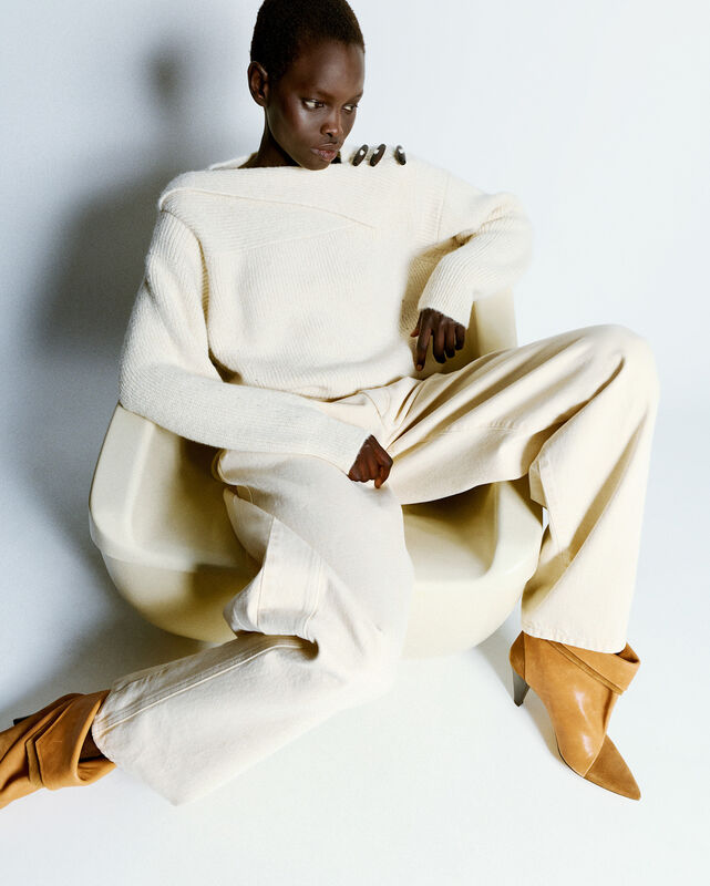 Модель в уютном белом свитере и светлых брюках, акцент на изысканных туфлях, передает ощущение комфорта и стиля