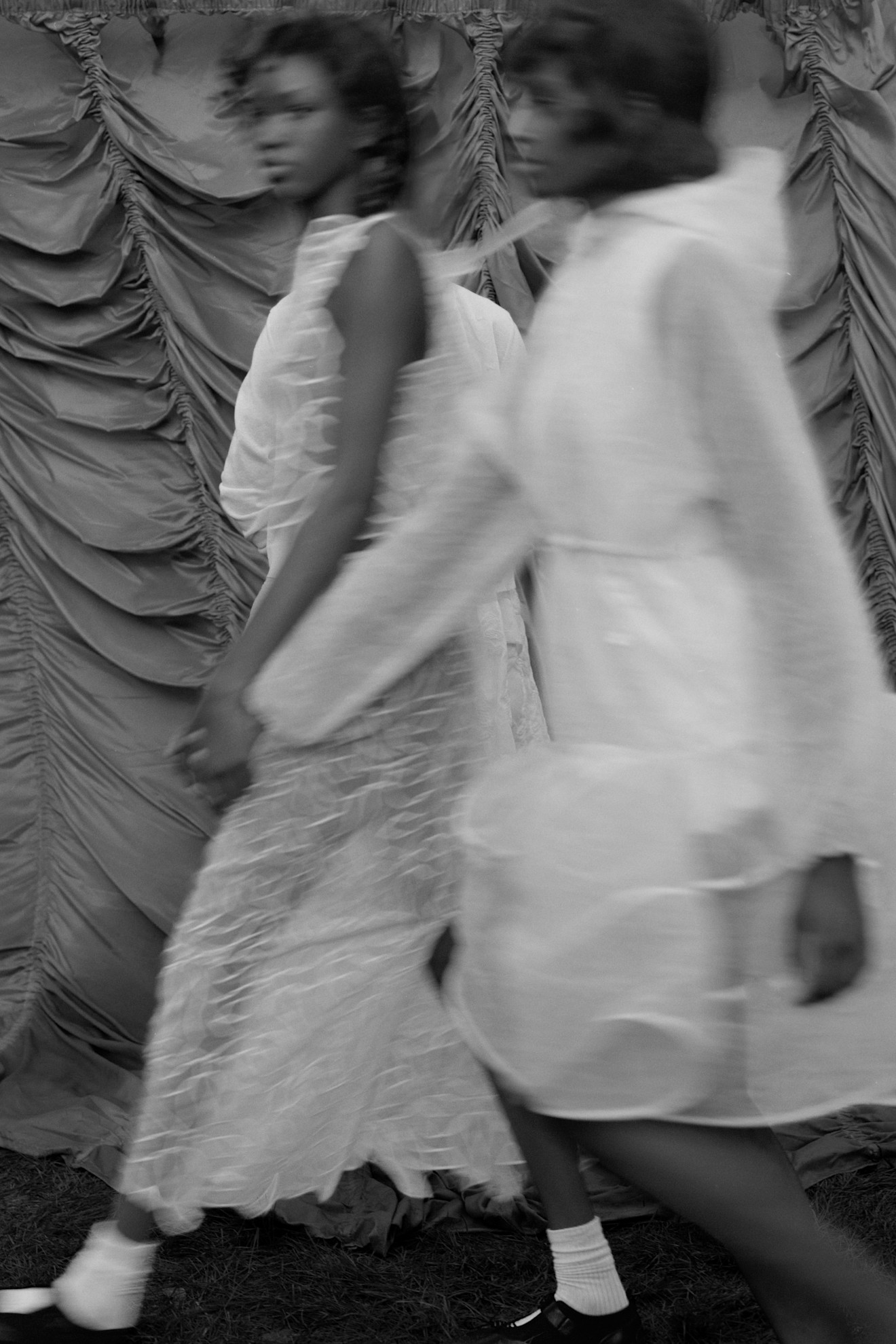 Две модели в полупрозрачных нарядах, эффектно движущиеся на фоне драпировки, передающие ощущение легкости и динамики