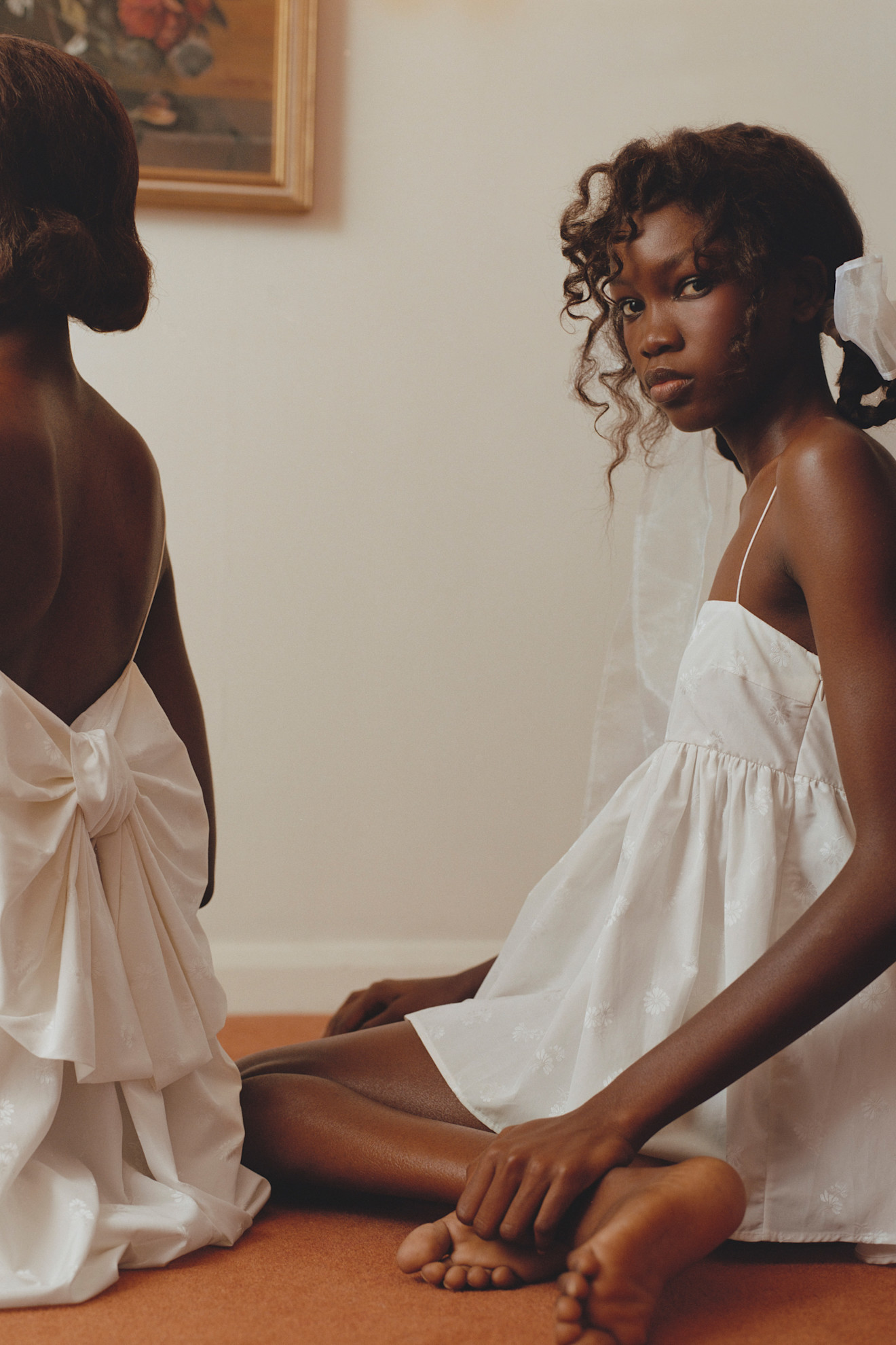 Две модели в белых платьях с объемными элементами, одна из них смотрит в камеру, создавая ощущение интима и нежности