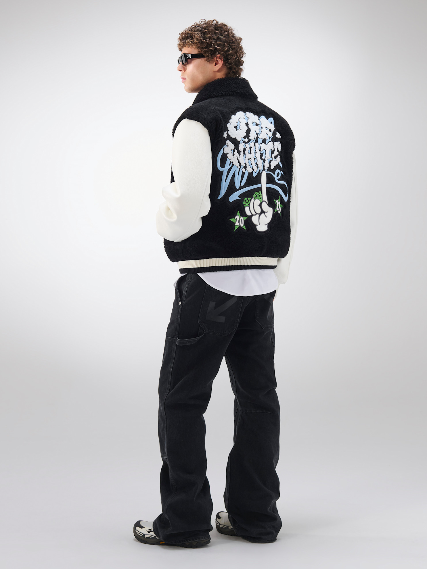 Черный жилет с графическим принтом на спине, дополненный белыми рукавами и темными джинсами, отражает уличный стиль