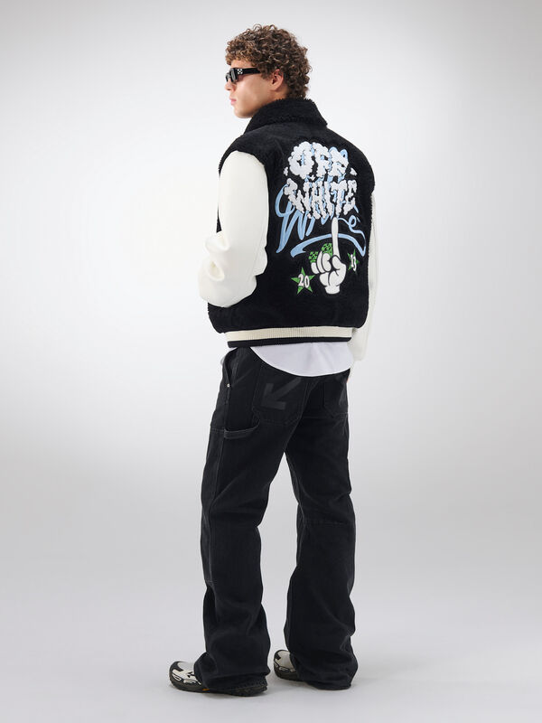 Черный жилет с графическим принтом на спине, дополненный белыми рукавами и темными джинсами, отражает уличный стиль