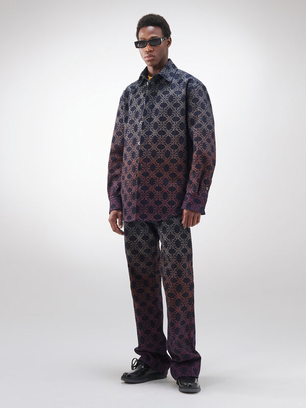 Модель в комплекте из рубашки и брюк с градиентным узором, создающим эффект перехода от темного к светлому, в стильных очках