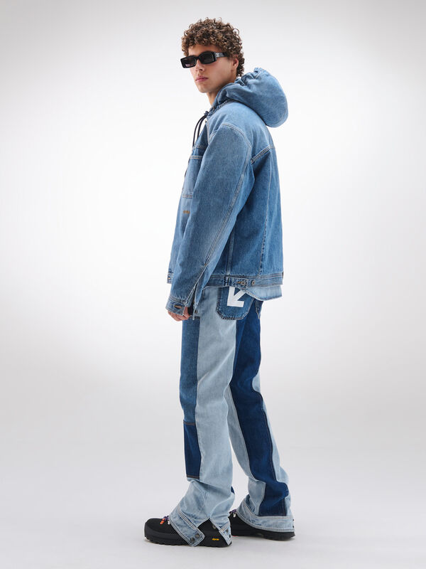Молодой человек в объемной джинсовой куртке с капюшоном и асимметричными джинсами, сочетание светлых и темных оттенков денима