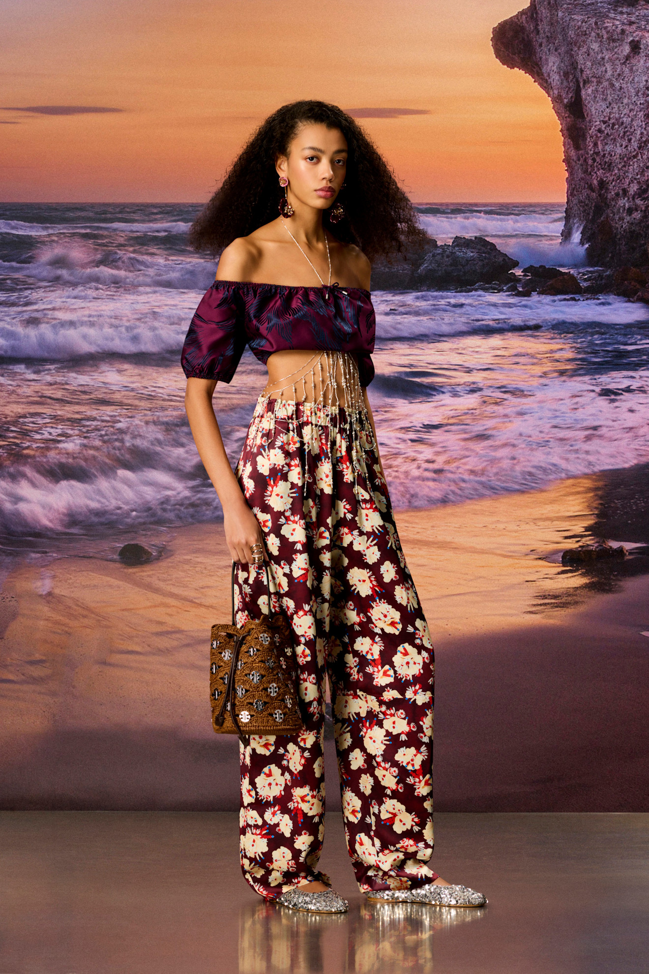 Объемный топ с короткими рукавами и широкие брюки с цветочным принтом подчеркивают летнюю атмосферу у моря