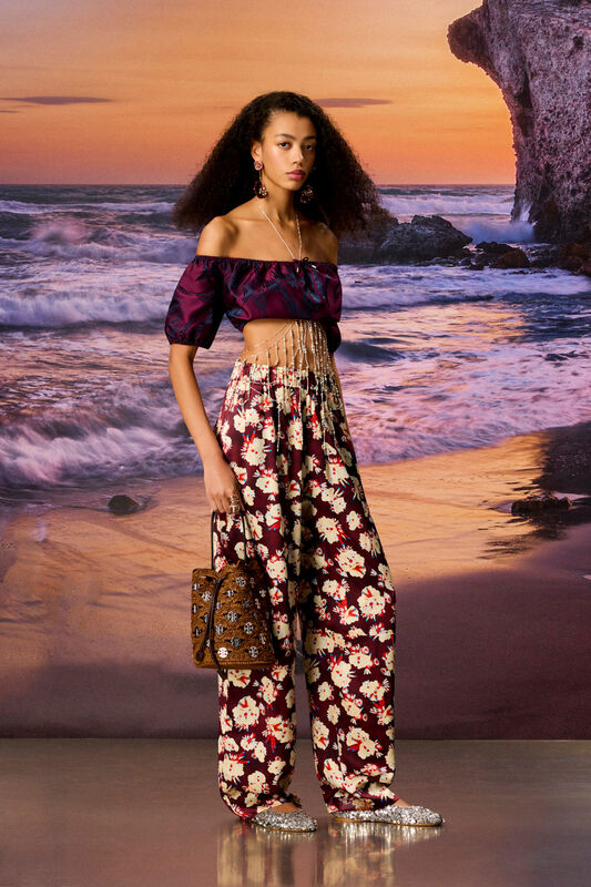 Объемный топ с короткими рукавами и широкие брюки с цветочным принтом подчеркивают летнюю атмосферу у моря