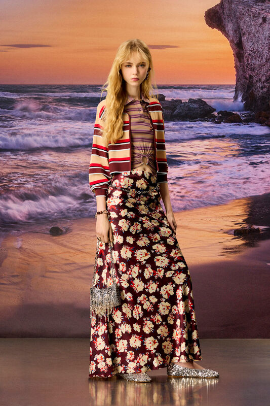 Стильный жакет в полоску и цветочная юбка создают яркий контраст, подчеркивая летнее настроение на фоне моря
