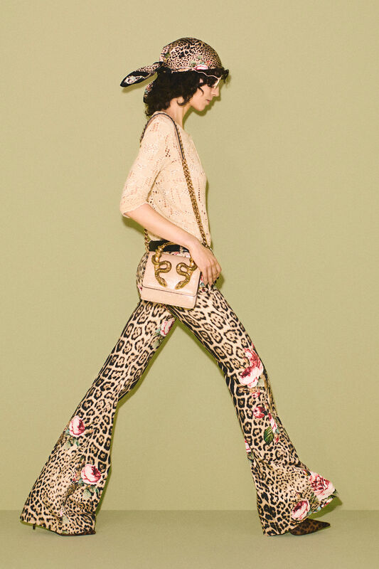Легкий вязаный свитер и расклешенные брюки с цветами на леопардовом фоне, завершенные стильной сумкой