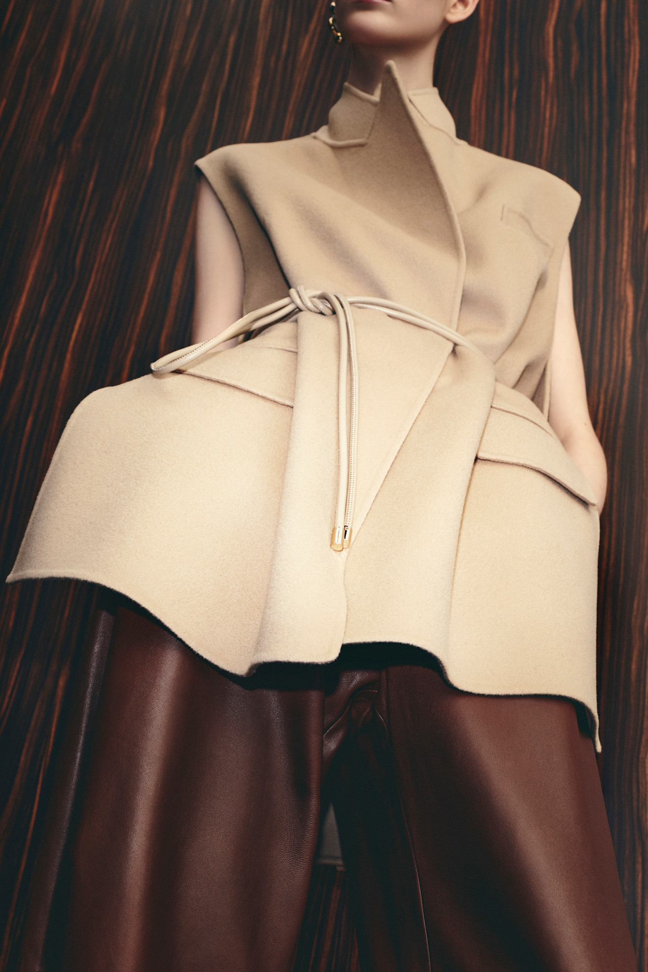 Элегантный бежевый жилет с асимметричным кроем и коричневыми кожаными брюками, создающими стильный силуэт