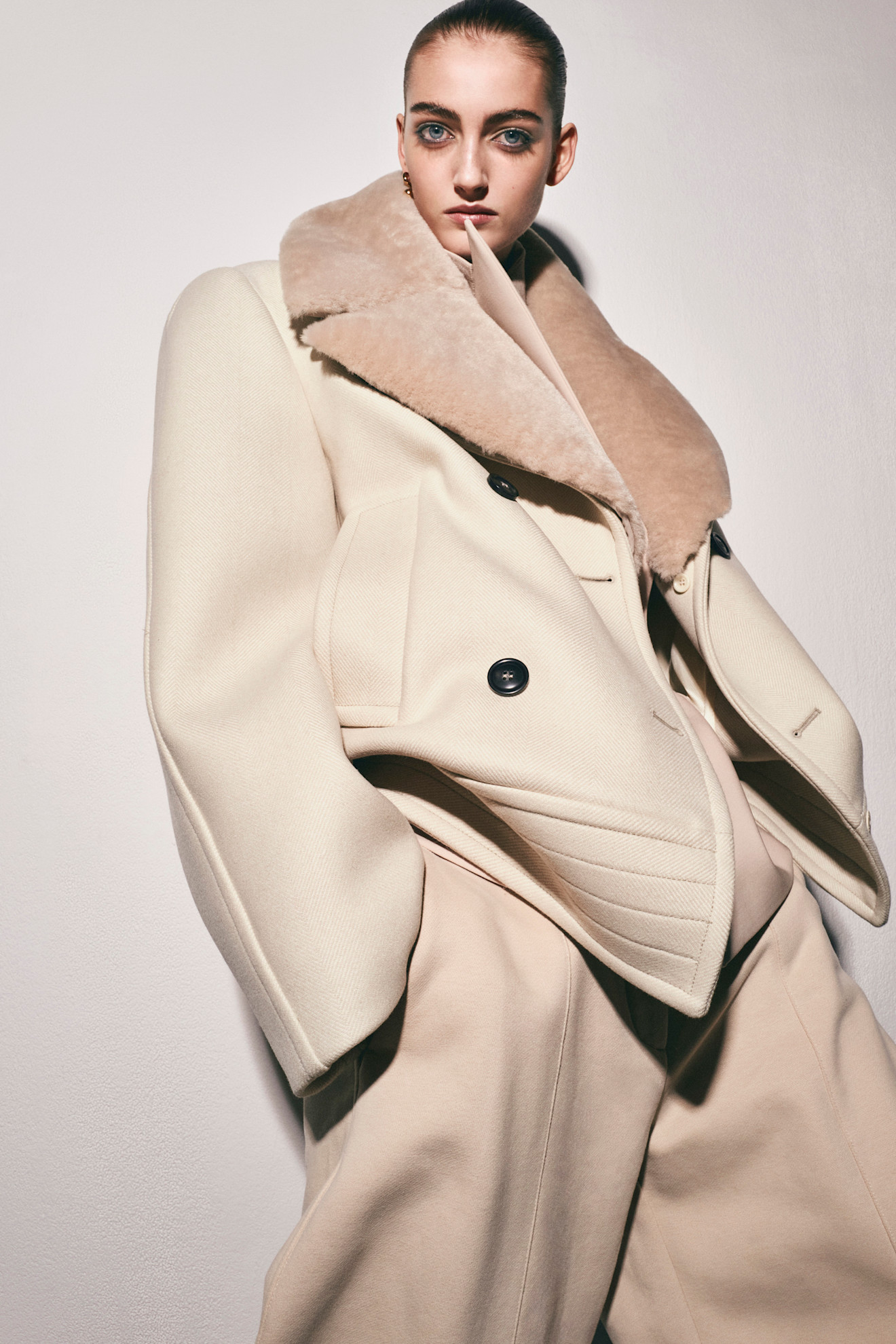 Стильное бежевое пальто с объемным воротником из меха, контрастирующее с мягкими линиями силуэта
