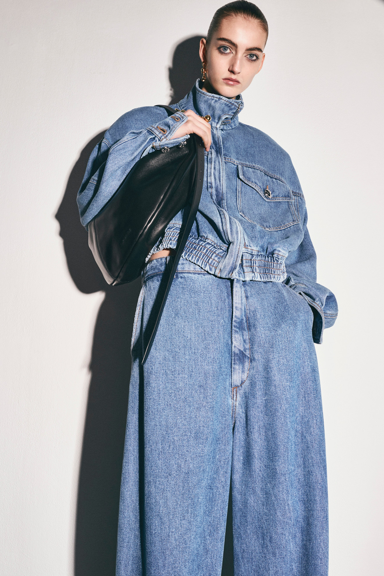 Объемный джинсовый комплект с укороченной курткой и широкими брюками, дополненный черной сумкой