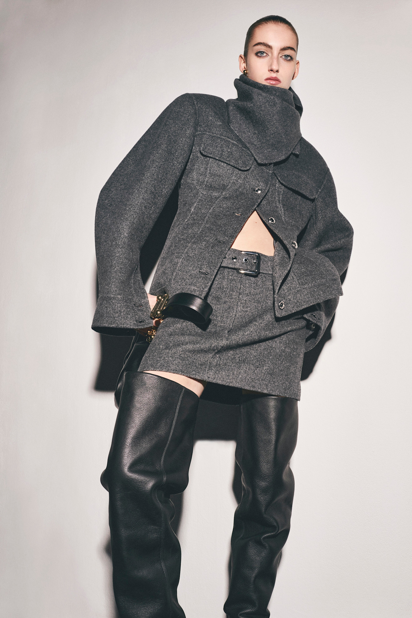Строгий серый жакет с высоким воротником и мини-юбкой, контрастирующий с кожаными чулками
