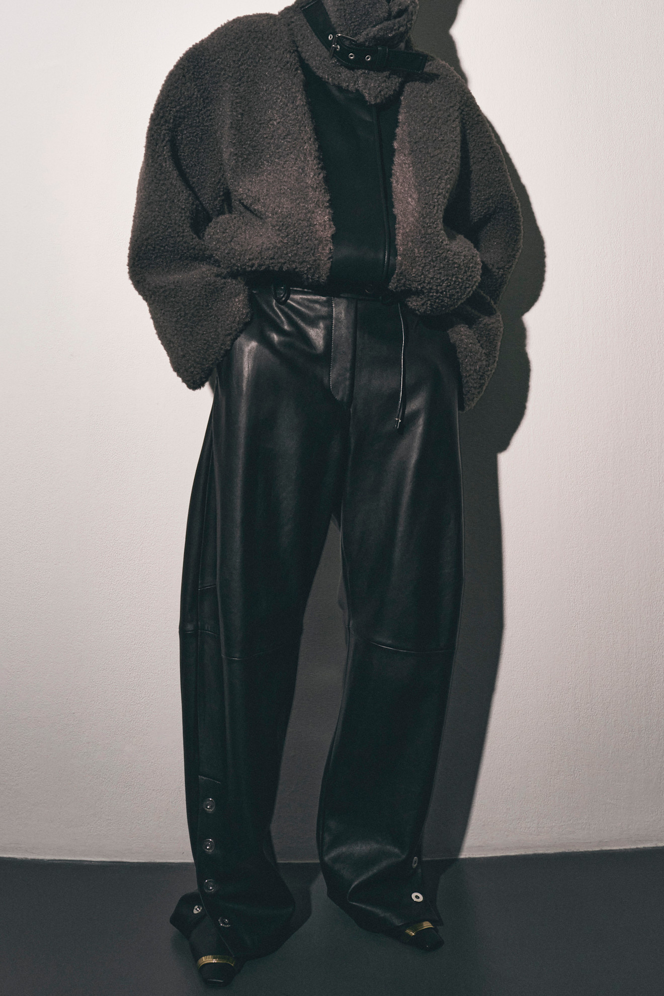 Модель в уютном сером жакете и кожаных брюках, подчеркивающих силуэт, с акцентом на детали кроя