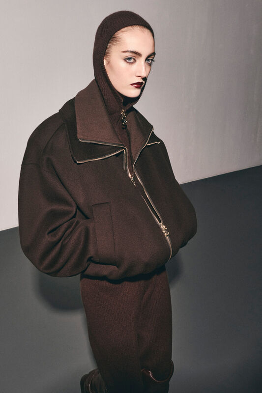 Объемный коричневый жакет с высоким воротником и капюшоном, дополненный строгими линиями и металлической фурнитурой