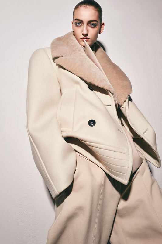 Стильное бежевое пальто с объемным воротником из меха, контрастирующее с мягкими линиями силуэта