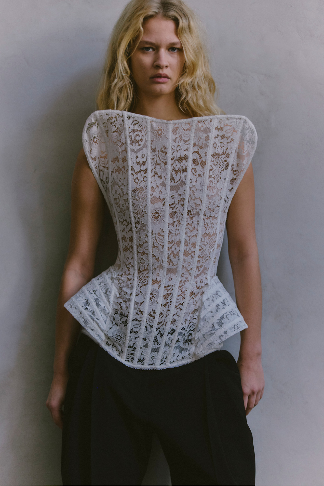 Корсетная блуза из белого кружева с объемными плечами, гармонично сочетающаяся с черными брюками, создает утонченный образ.