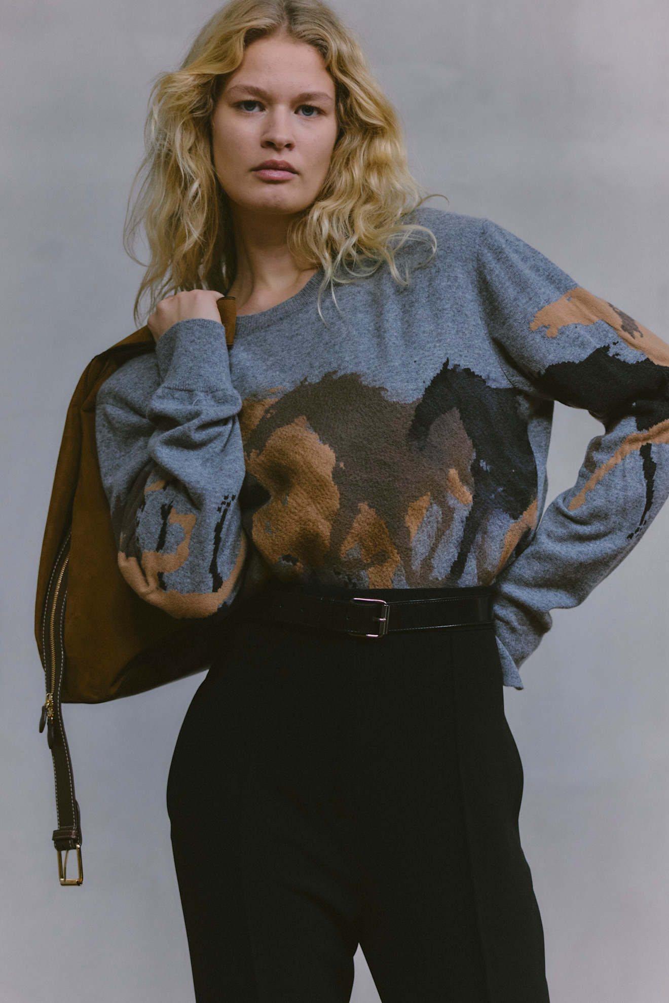 Уютный серый свитер с абстрактным рисунком лошадей, дополненный черным поясом и сумкой, придающим образу завершенность