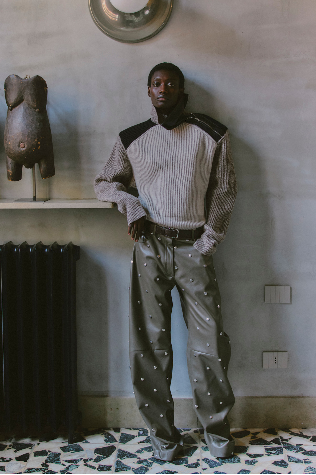 Модный свитер с текстурированными рукавами и кожаными брюками с металлическими элементами, создающими эффектный силуэт