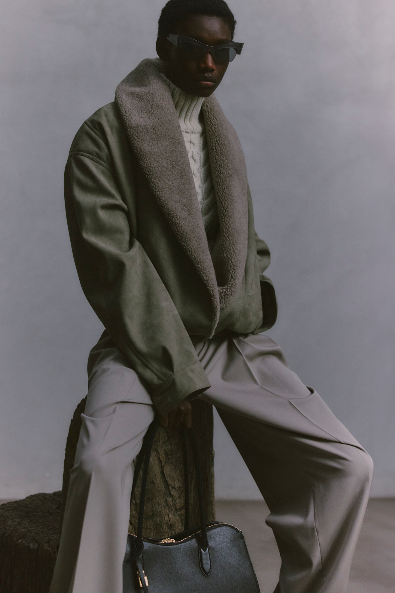 Уютный зеленый жакет с меховым воротником, вязаный свитер и светлые брюки, строгий стиль с черной сумкой в руках