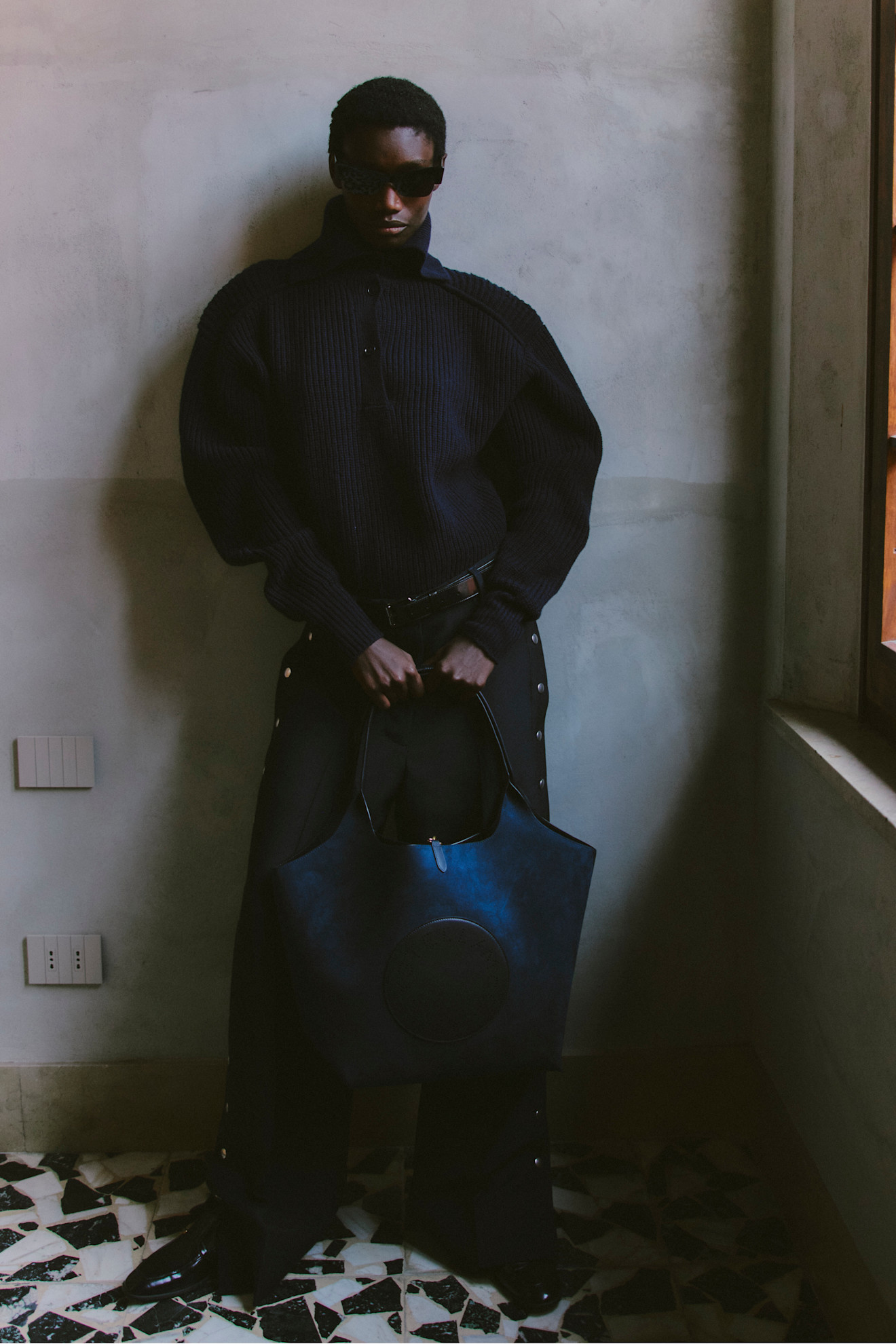 Объемный черный свитер с высоким воротником и широкими рукавами, дополненный стильной сумкой, создаёт атмосферу уюта и элегантности