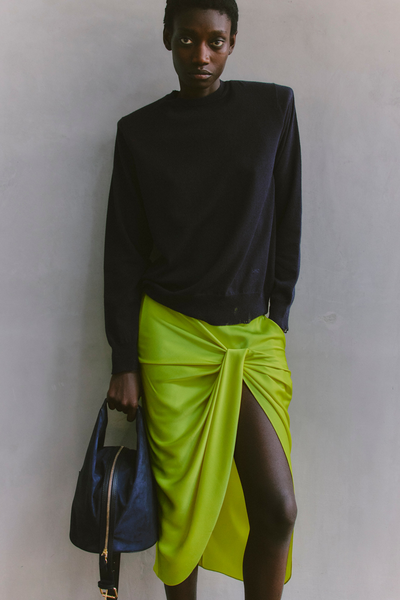 Черный свитер в сочетании с яркой зеленой юбкой с разрезом, создают смелый контраст и выразительный образ