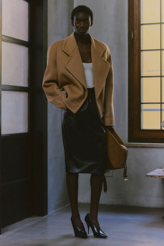 Объемный бежевый пиджак в сочетании с кожаной юбкой, создающий контраст между уютом и строгостью