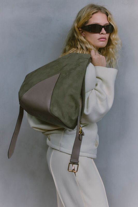 Модель в светлом наряде с рюкзаком из замши и кожи, добавляет нотку утонченности и современности в образ