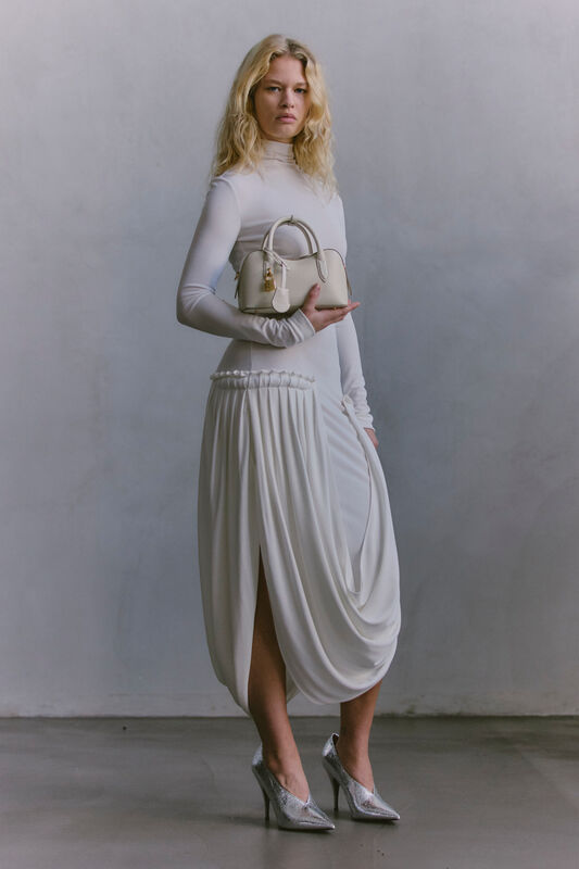 Элегантное белое платье с драпировкой и высоким разрезом, дополненное стильной сумкой