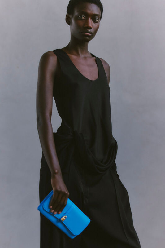 Черное платье с драпировкой и яркой синей сумкой, акцентирующее внимание на минимализме и элегантности