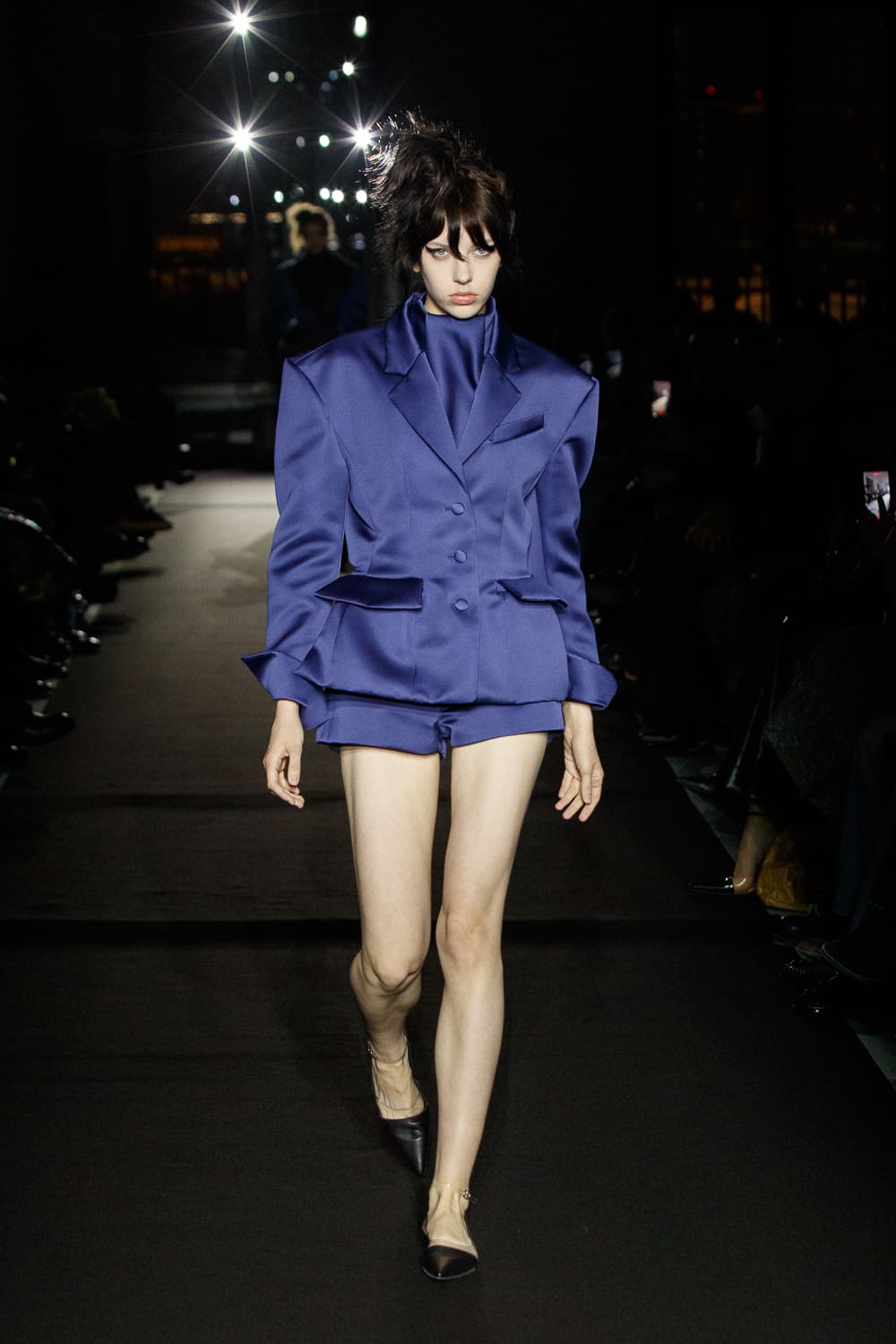 Ярко-синий жакет с объемными плечами и шортами, создающий эффектный контраст с нежной кожей модели