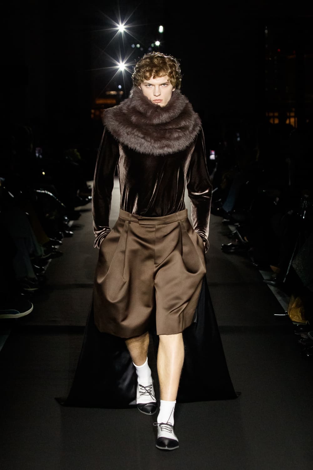 Мужчина в бархатной кофте с меховым воротником и широких шортах, излучающий элегантность и тепло