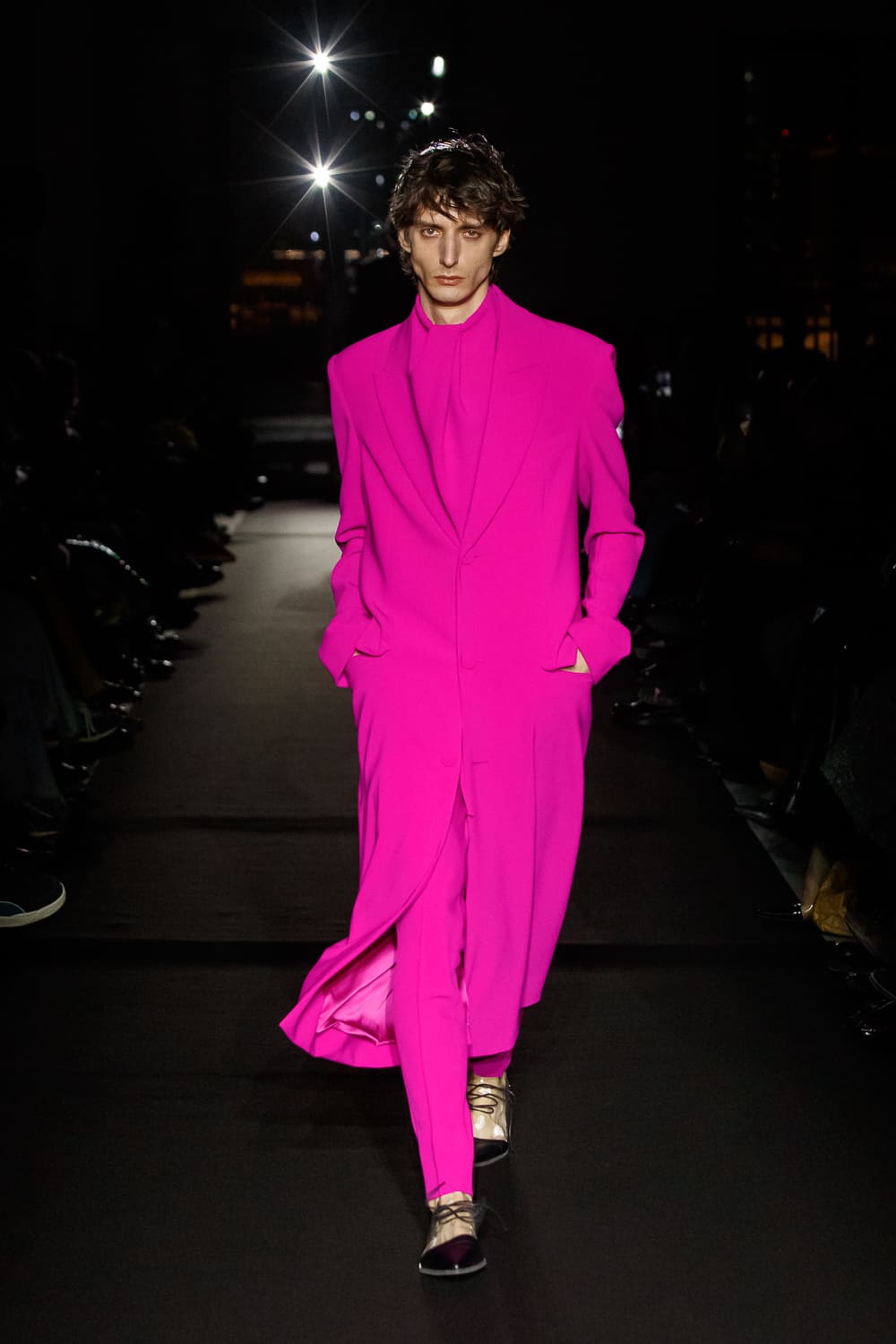 Яркий розовый костюм с длинным пиджаком и строгими линиями, привлекает внимание своей смелостью и современным стилем