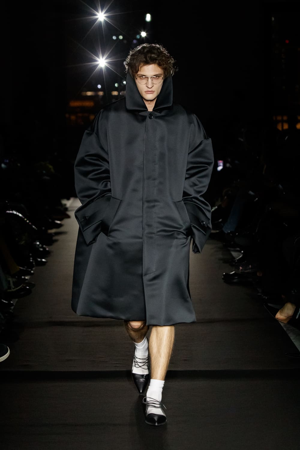 Гладкое черное пальто с капюшоном и объемными рукавами, создает эффектный образ в сочетании с минималистичными деталями