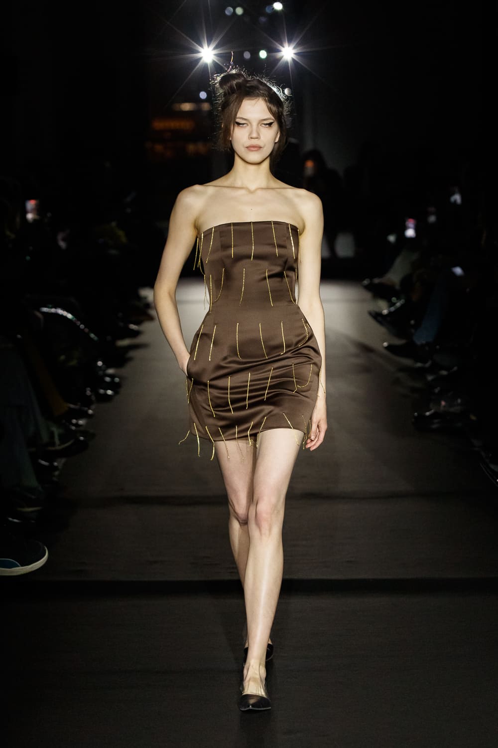 Обтягивающее коричневое платье с золотыми акцентами, подчеркивающее фигуру, излучает элегантность и современность