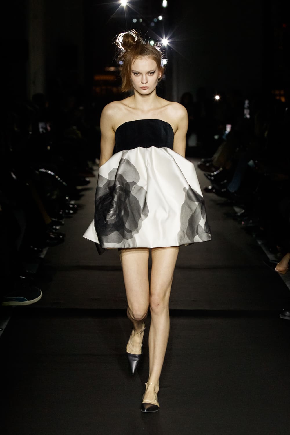 Минималистичное платье с черным корсетом и объемной юбкой, украшенной полупрозрачными цветами, создает игривый образ